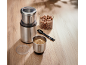 Metal electric grinder with whole and ground hazelnuts on a wooden background.