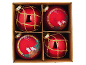 Four red Christmas baubles in a cardboard box, two with a golden grid pattern and two with candles and foliage.