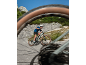 Man cycling uphill on an electric mountain bike, seen through a blurred bicycle wheel.
