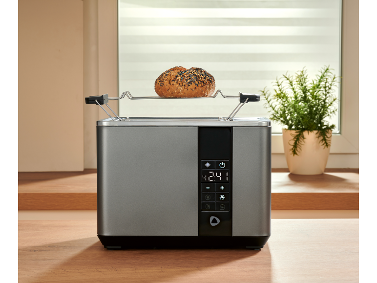 Grey toaster with a digital display and a bun on the warming rack, on a wooden kitchen counter.