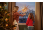 Woman and girl hanging a paper Christmas star in the window next to the tree.
