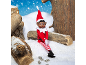 Christmas elf sitting in the snow between wooden logs.