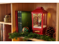 Christmas decoration with red lantern featuring Santa, books, and garland on a wooden shelf.