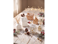 Festive ceramic houses and reed diffusers on a snowy wooden table.