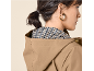 Woman in a beige hooded jacket with a houndstooth pattern lining, golden earrings.