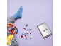 A child plays with superhero building blocks, following instructions on a tablet.