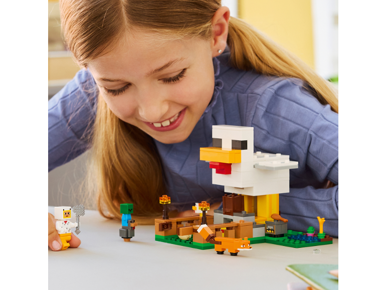 Girl playing with a building toy set featuring a large chicken, a fox, and human figures.