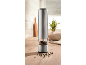 Metal pepper grinder with a transparent section filled with peppercorns on a wooden kitchen counter.