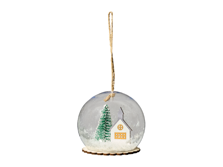 Christmas snow globe ornament with a house and tree inside, hanging by a string.