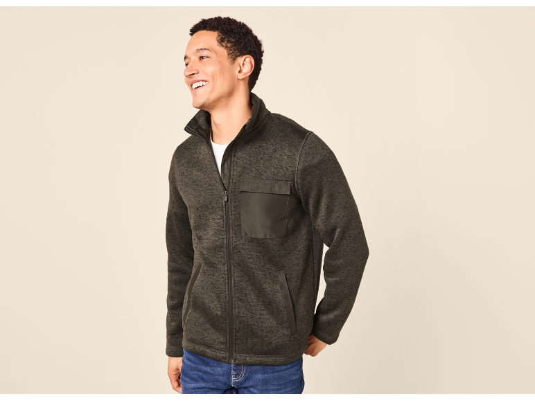 Man in a dark grey fleece jacket with a chest pocket, smiling and looking to the side.