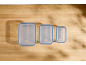 Three transparent food containers with blue lids on a wooden table.