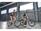 Two people on electric bikes in an indoor parking garage.