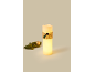 Decorative LED candle with burlap band and pine ornament, next to a pine branch.