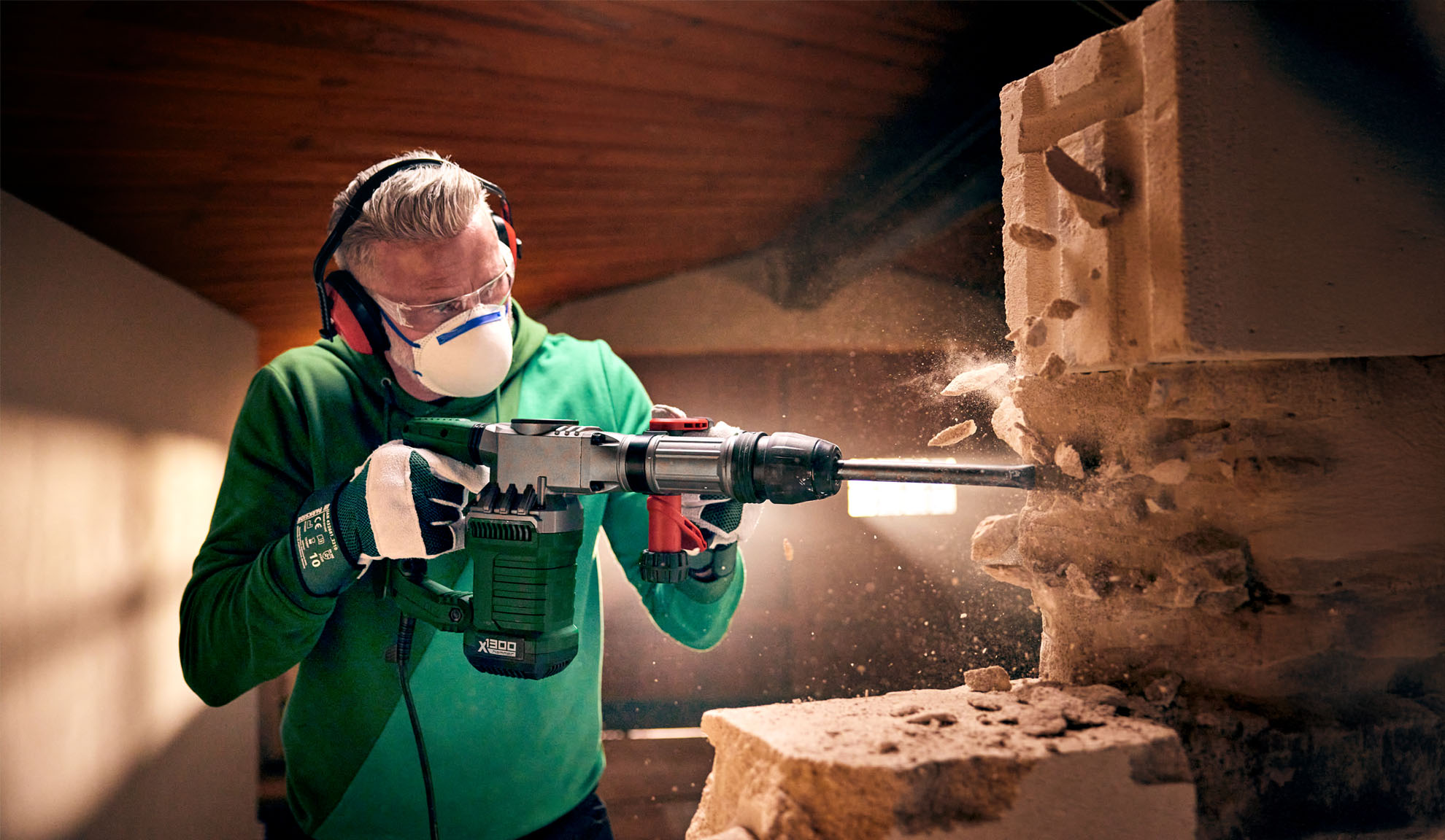 A man uses a Worx X-BRUSHLESS demolition hammer to break a concrete block.