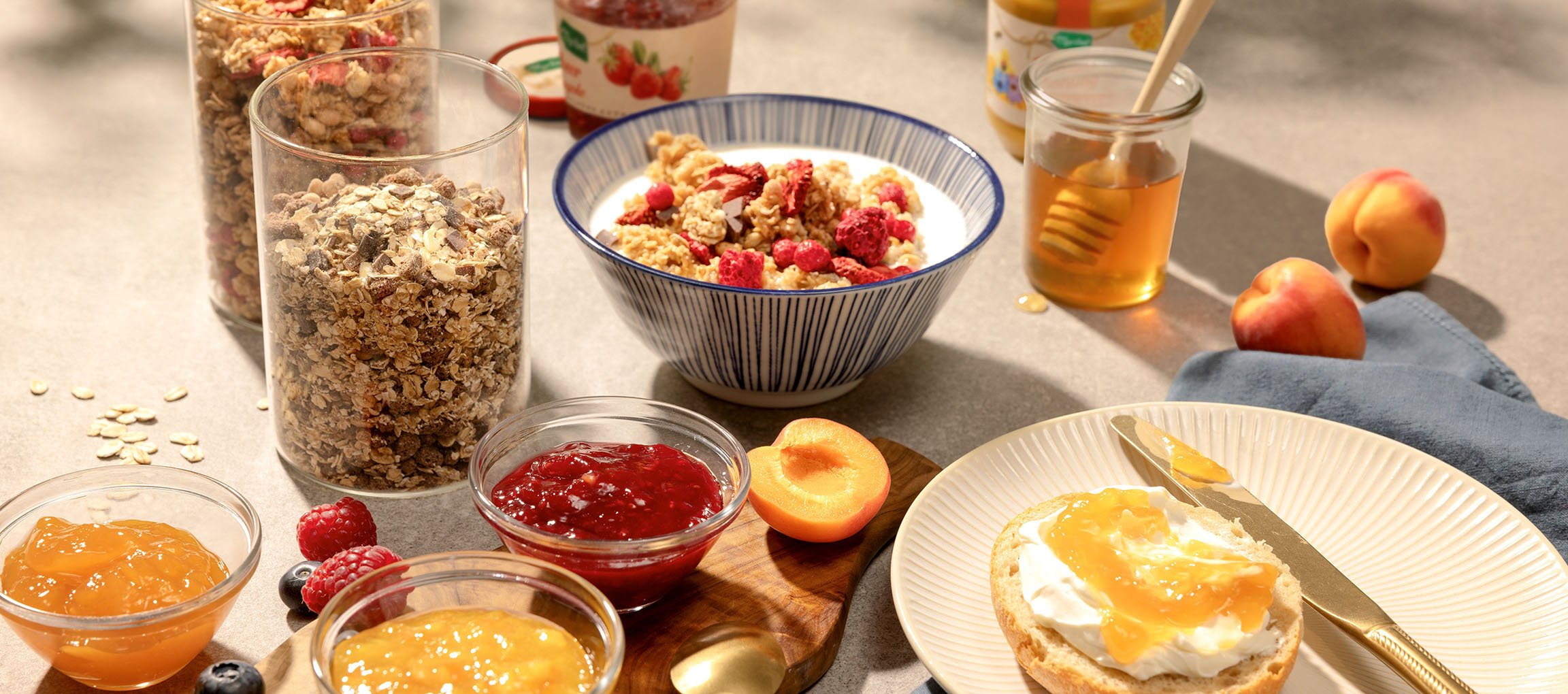Breakfast spread with granola, milk, honey, jams, and a roll with cream cheese.