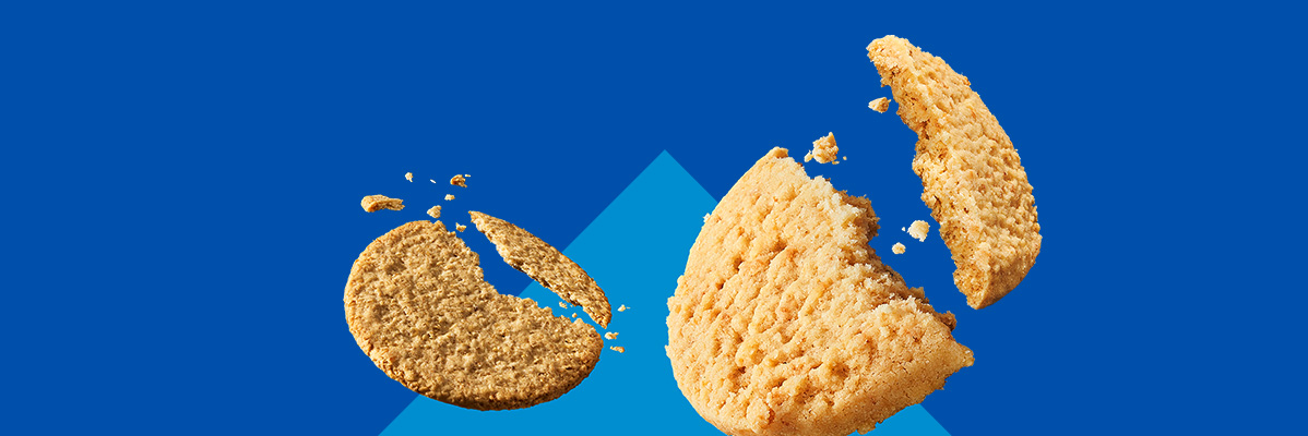 Two broken cookies with crumbs against a blue background with a subtle triangle.
