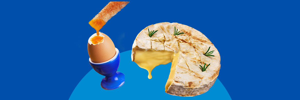 A soft-boiled egg in a blue egg cup with a toast dipper, next to a baked cheese.