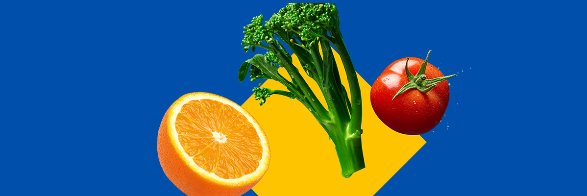 An orange half, broccoli, and a tomato on a blue and yellow background.