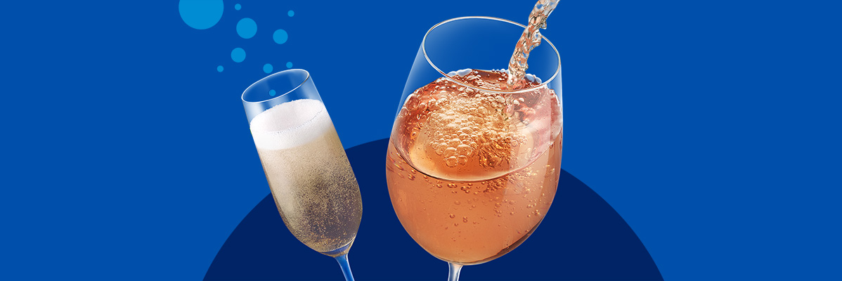 Two glasses of sparkling beverages, one being poured, against a blue background.