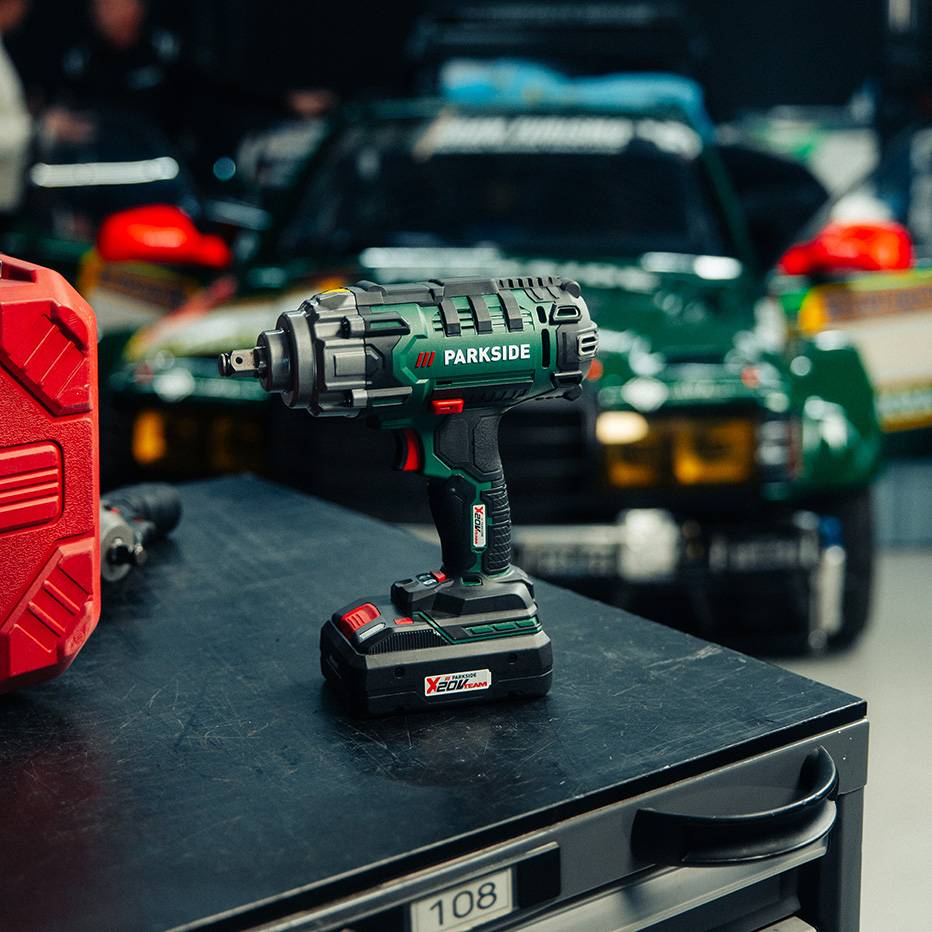 Cordless impact wrench on a workbench with a rally car in the background.