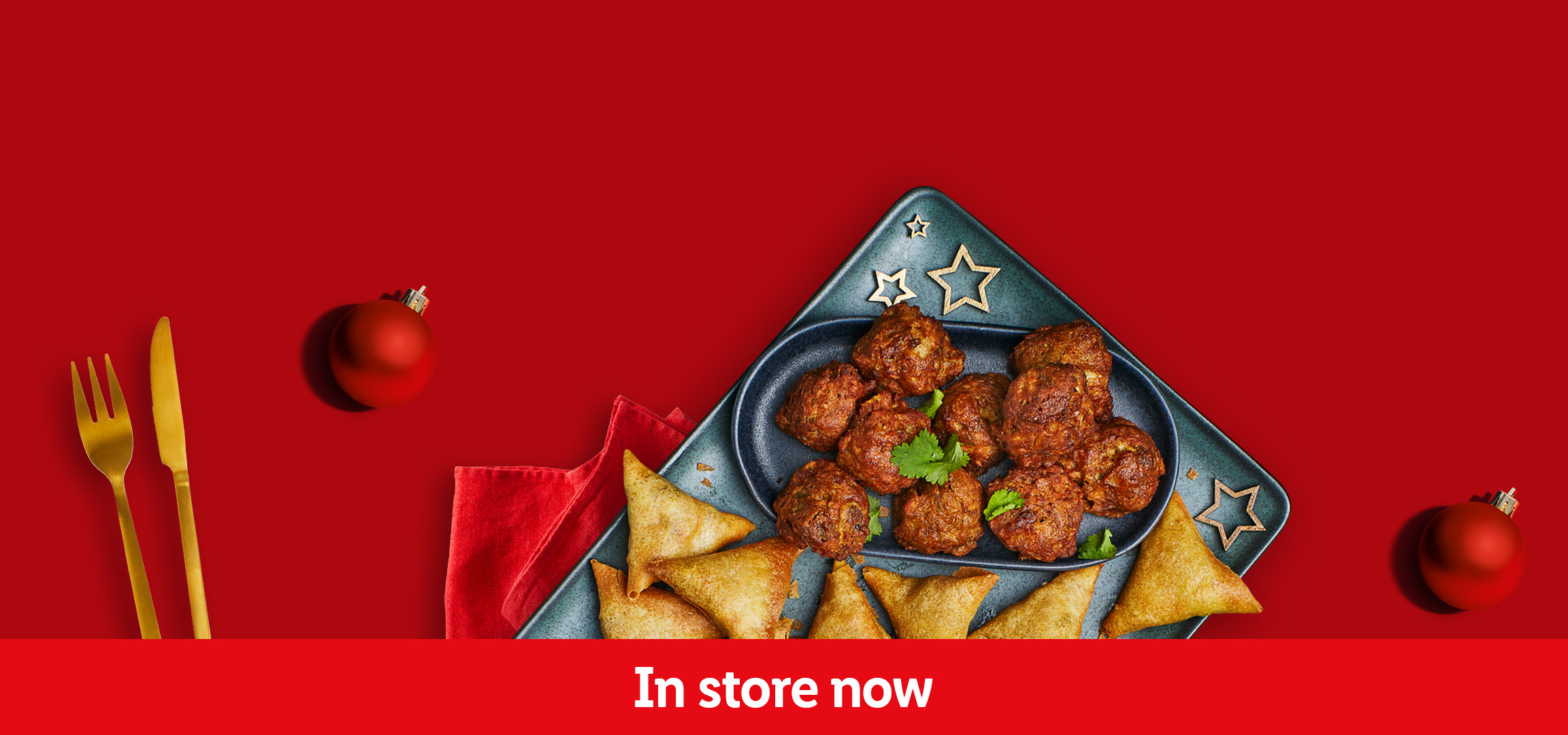 Christmas party food: chicken skewers, samosas, and meatballs on a red background. In store now.