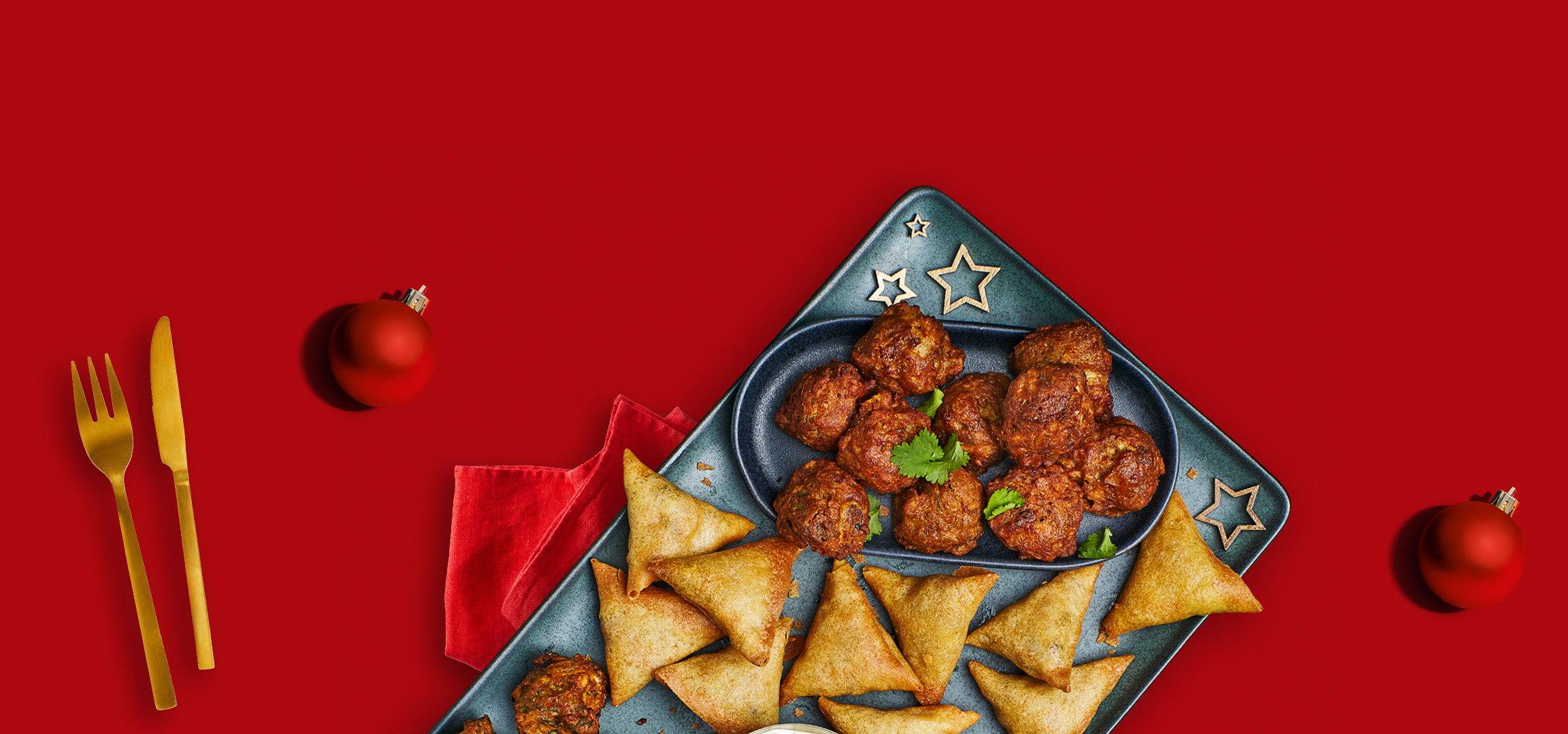 Chicken satay skewers, falafel, and samosas on a red background with Christmas ornaments.