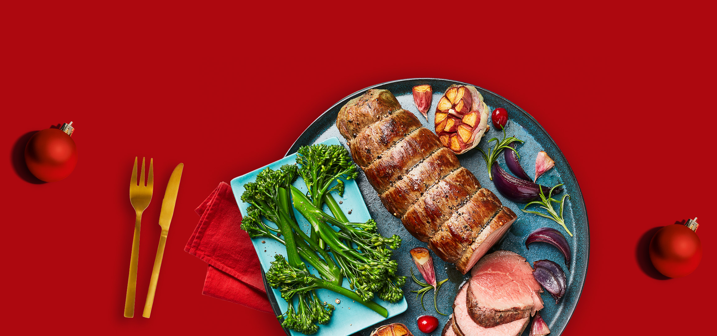 Christmas feast with roasted meats, vegetables, and golden cutlery on a red background.