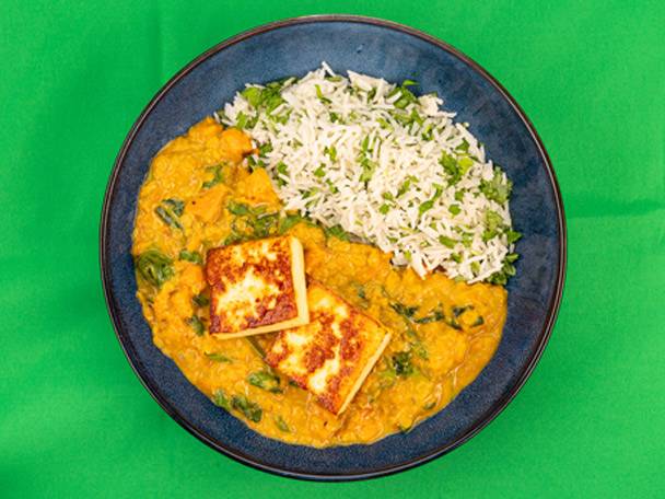 Paneer curry with rice and chickpeas on a blue plate.