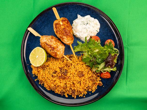 Chicken kofta skewers with couscous, salad, lime, and a side of tzatziki.