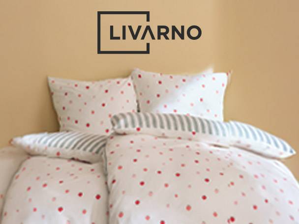 White bedding with red polka dots and striped accents on a bed.