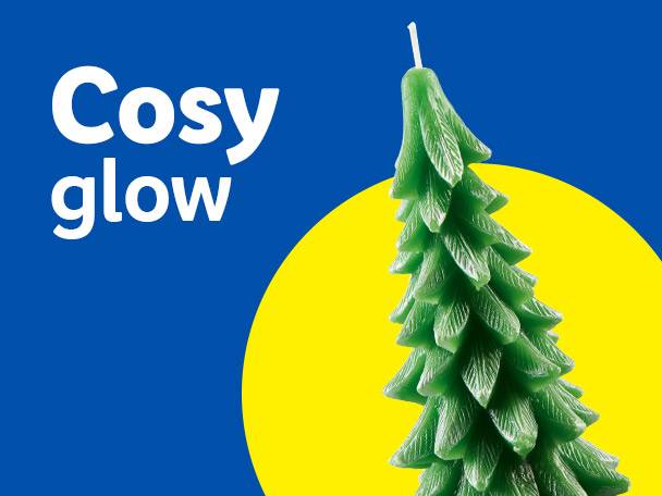 Green Christmas tree candle with 'Cosy glow' text on a blue and yellow background.