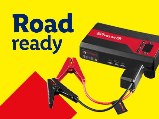 A portable jump starter with jumper cables on a yellow and red background, text reads 'Road ready'.