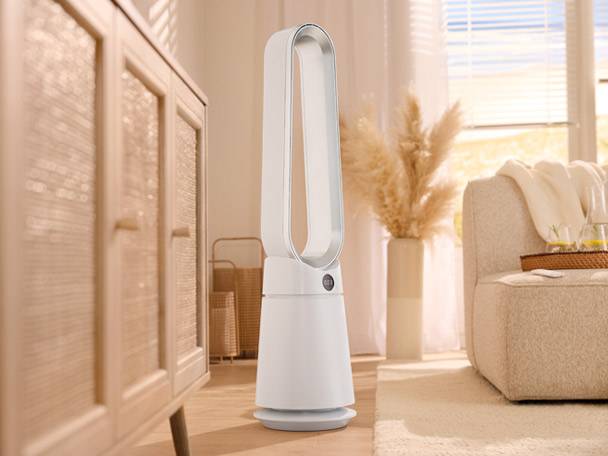 White bladeless tower fan in a bright living room with a light wood cabinet and sofa.
