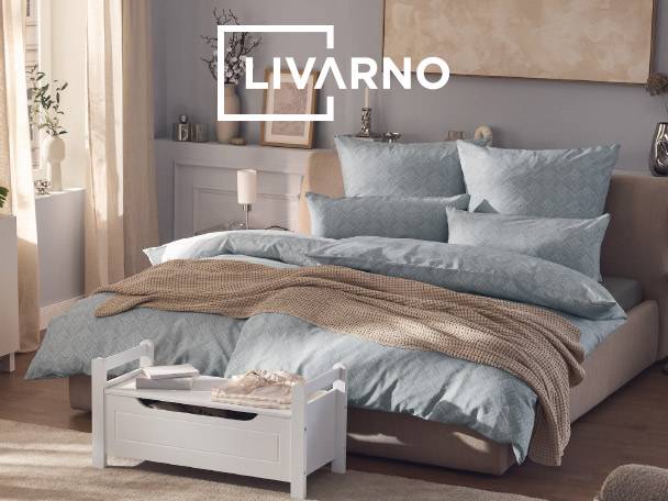 Bedroom with a bed featuring light blue patterned bedding, a brown knitted throw, and a white storage bench.
