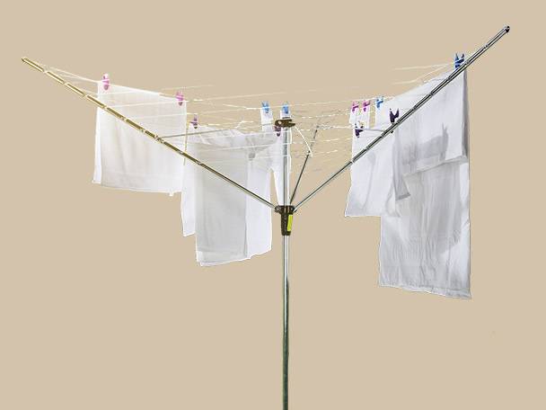 White laundry drying on a rotary clothesline with colorful pegs against a plain background.