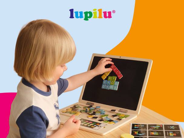 Child playing with a wooden laptop toy with magnetic letters and numbers