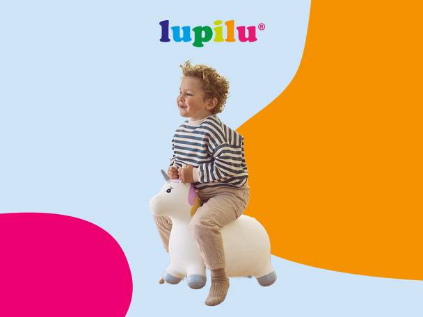 Happy child on a unicorn bouncy toy, with colorful background shapes.