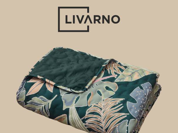 Quilted blanket with a tropical leaf pattern in green, beige, and grey.