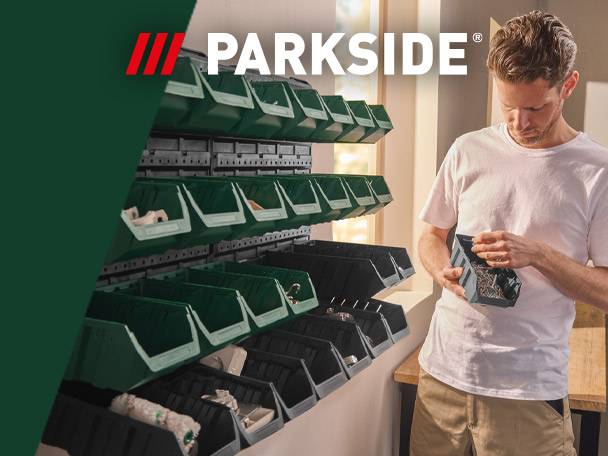 A man organizing small parts in a storage bin system with many green and black bins.