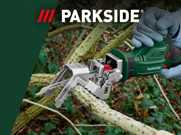 A person using a green electric pruning saw to cut a tree branch in a garden.