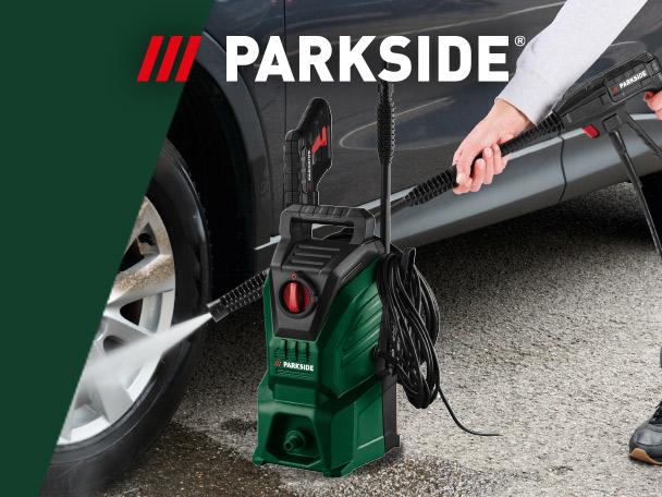 Green pressure washer cleaning a car wheel, with a person holding the spray gun.