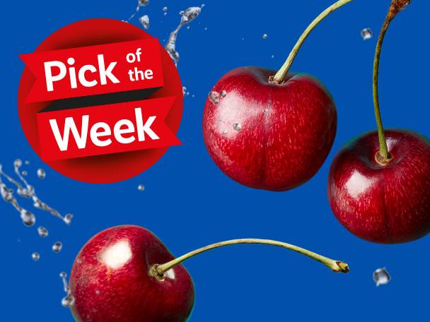Three juicy cherries, one with a stem, are featured against a vibrant blue background with water droplets, promoting them as 'Pick of the Week'.