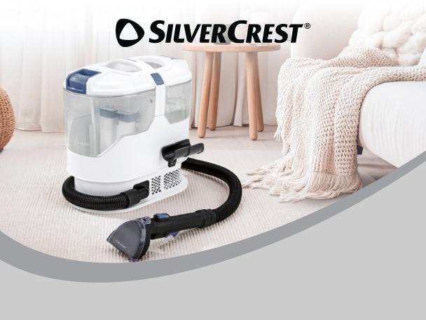 A portable carpet and upholstery cleaner on a rug next to a sofa.