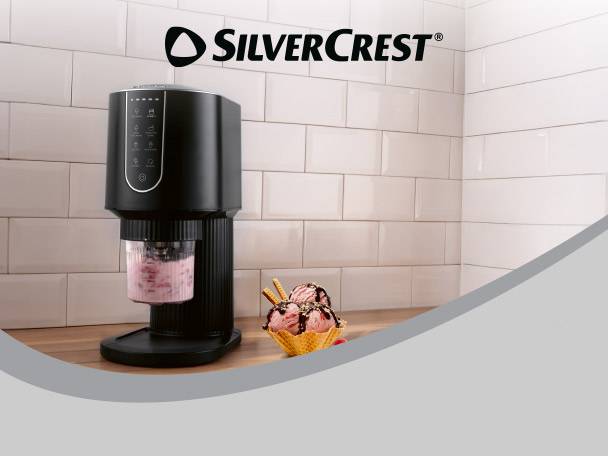 Black ice cream maker with a cup of pink ice cream and two scoops in a waffle cone.