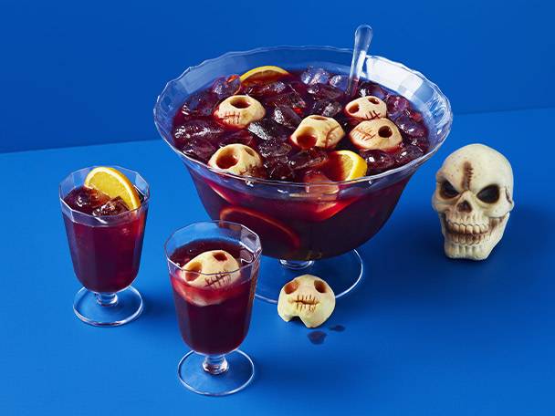 Halloween punch with skull-shaped cookies and a decorative skull on a blue background.
