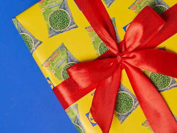 Gift wrapped in yellow paper featuring Lidl's British Garden Peas, tied with a red ribbon.