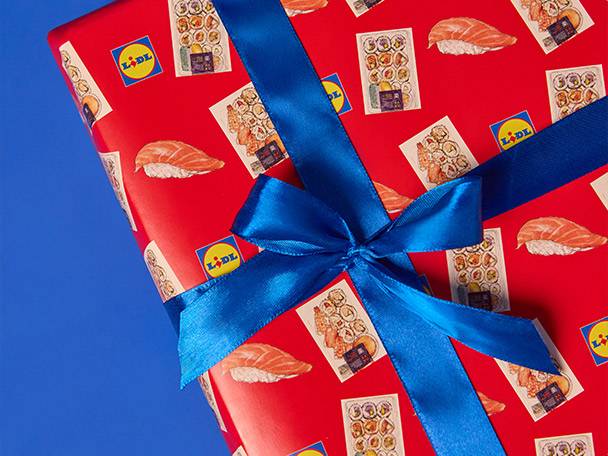 Lidl-branded red gift wrap with sushi and salmon nigiri, tied with a blue ribbon.