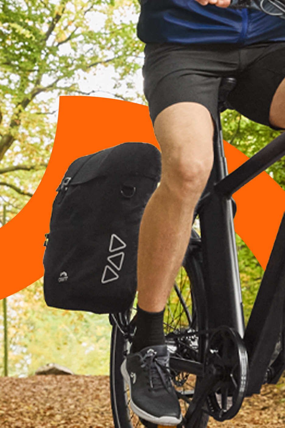 Cyclist with a black bicycle pannier bag on a bike in a forest setting.