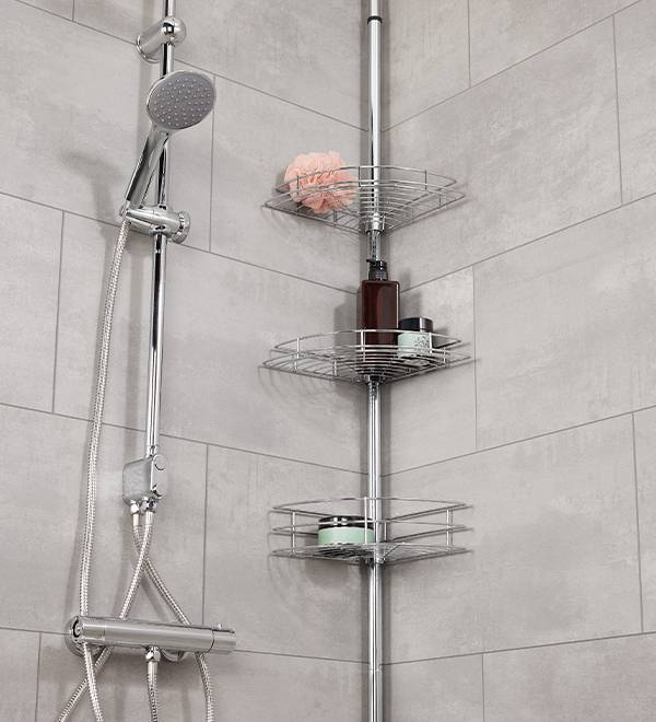A chrome corner shower caddy with three shelves holds toiletries and a shower head is mounted on the wall.