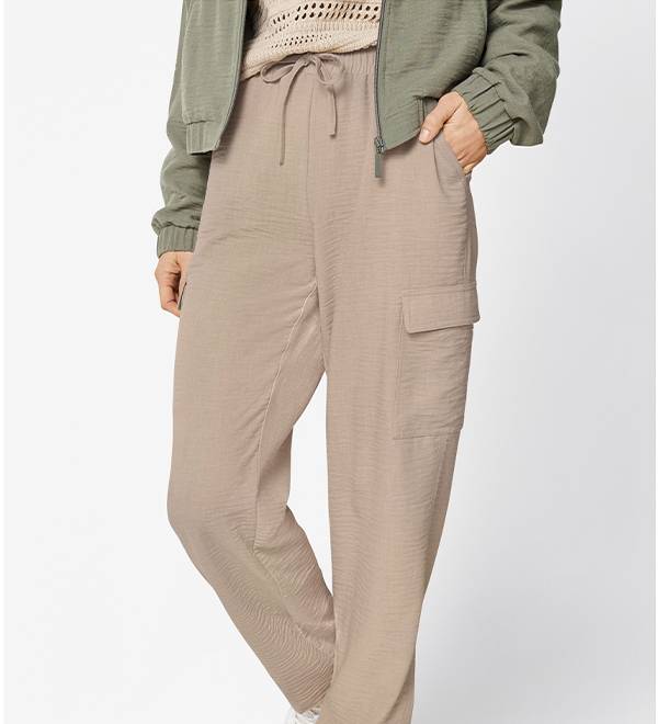 Beige cargo pants with drawstring waist, paired with a green bomber jacket.